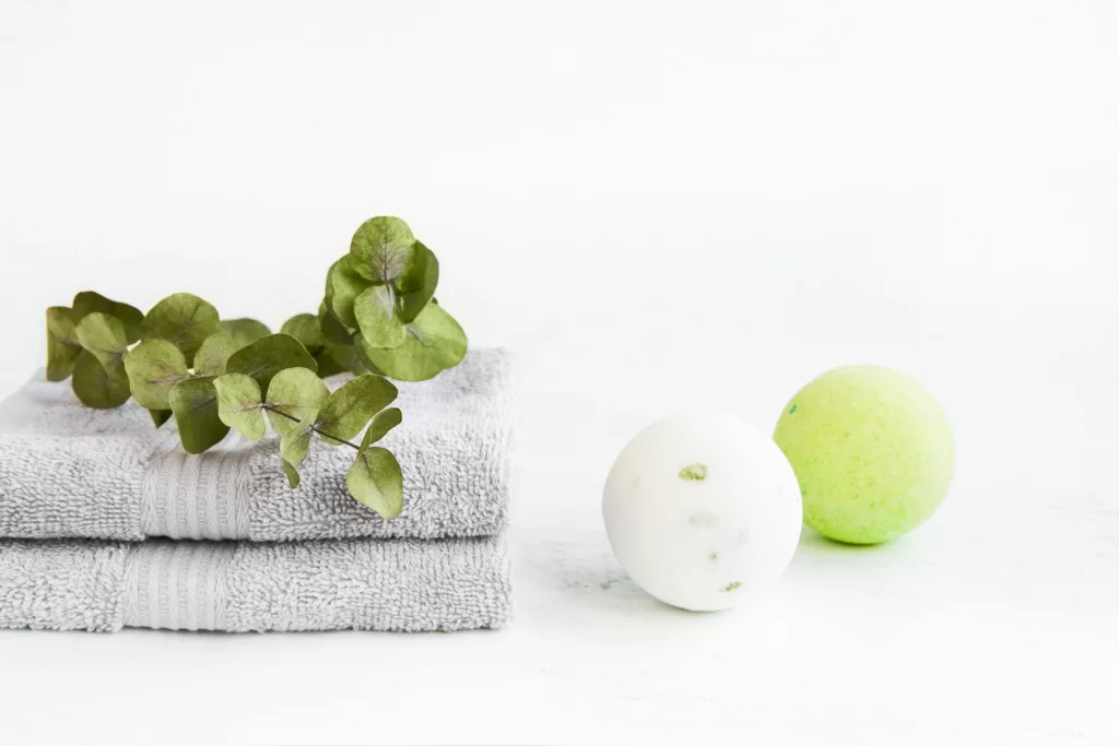 SPA concept. Bath bombs, eucalyptus and two gray towels on light background. Copy space
